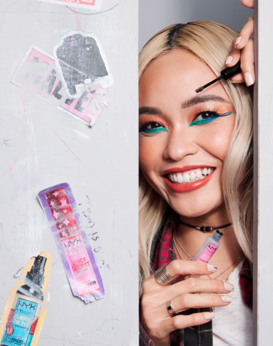 Picture of a model wearing bright, bold eyeshadows and holding the brow brush from NYX x Netflix. | ASOS Style Feed