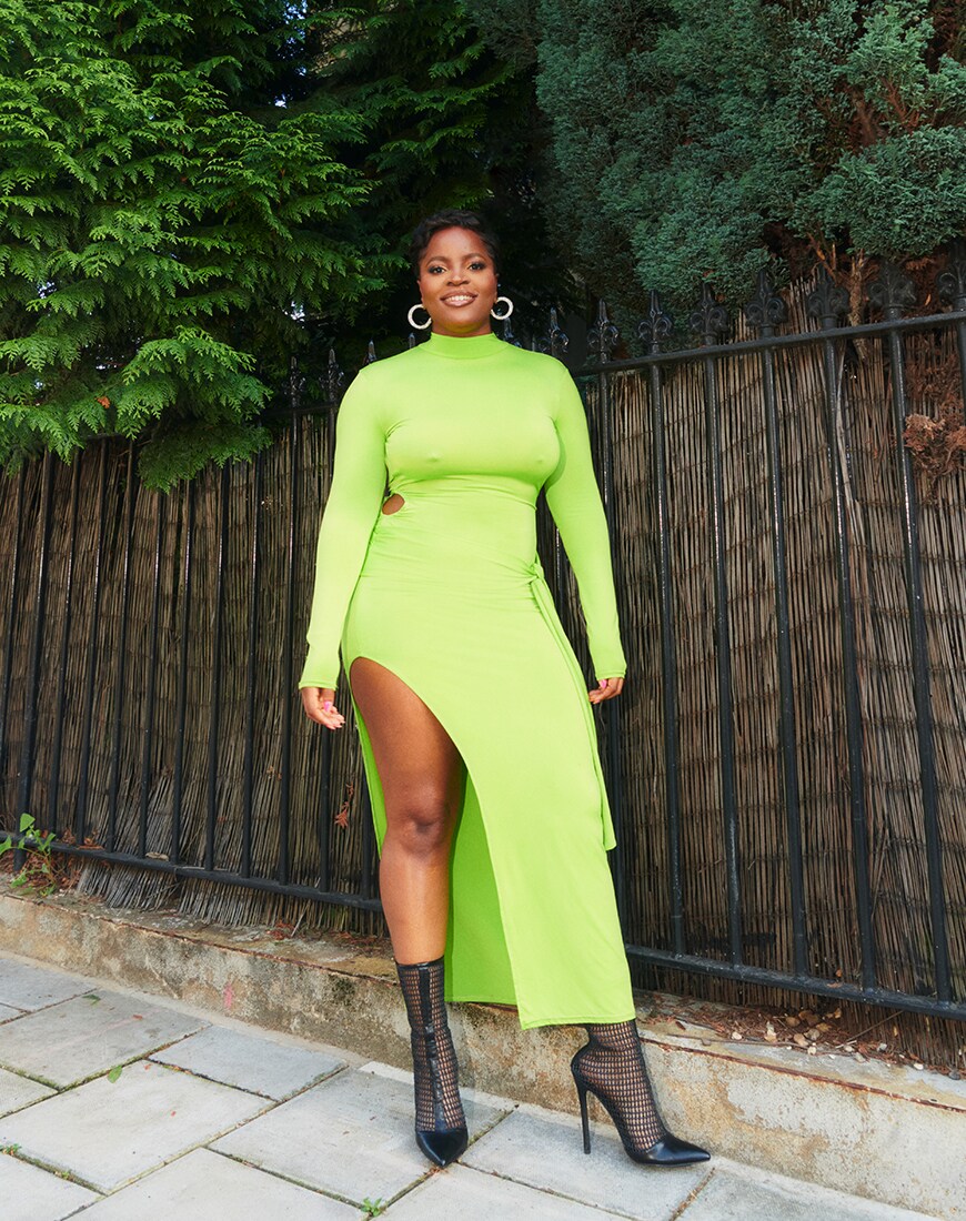 Tolly stands in front of trees and a big fence in a neon green cut-out midi dress and mesh shoe-boots | ASOS Style Feed 
