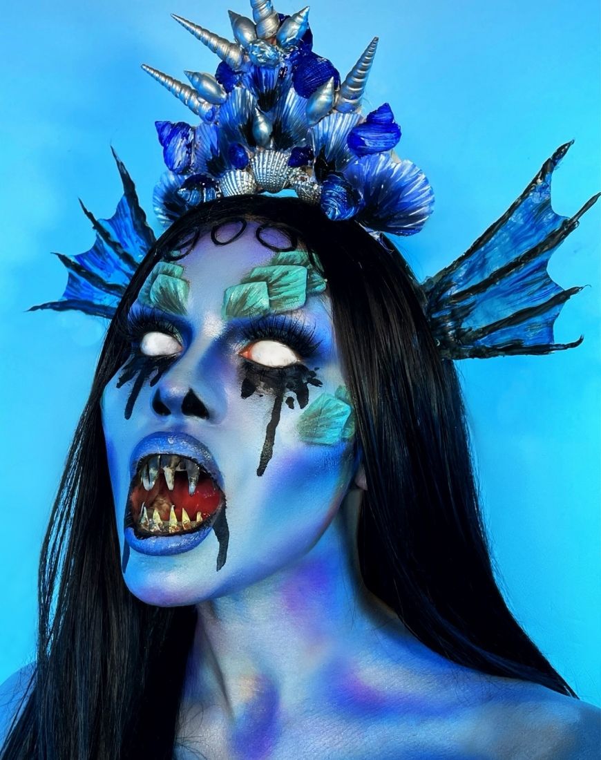 Amber has created a blue Siren-esque makeup look complete with fake scales, white contacts and fake teeth. | ASOS Style Feed