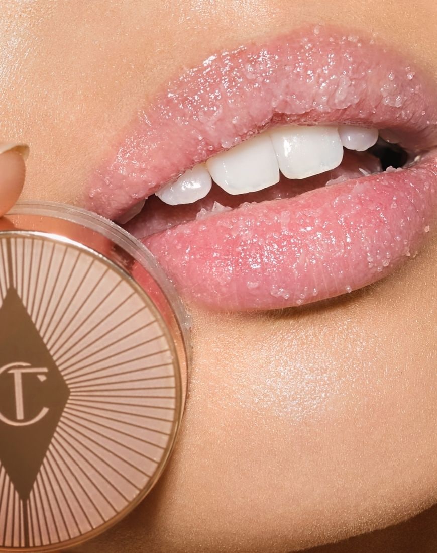 A picture of a model having applied the Charlotte Tilbury x ASOS Exclusive Lip Scub to her lips. She's also holding the pot up to the camera so we can see the CT logo. | ASOS Style Feed