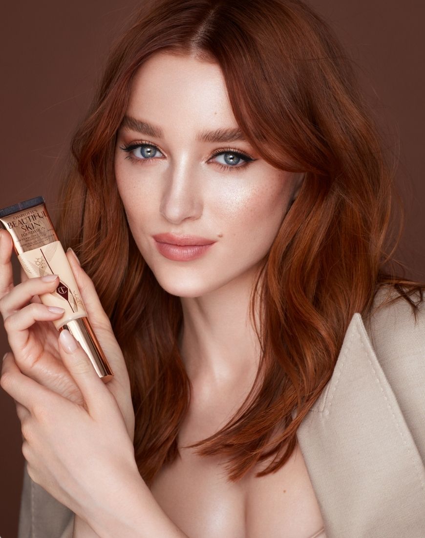 Bridgerton star Phoebe Dynevor poses with the brand-new Beautiful Skin Foundation from Charlotte Tilbury. | ASOS Style Feed