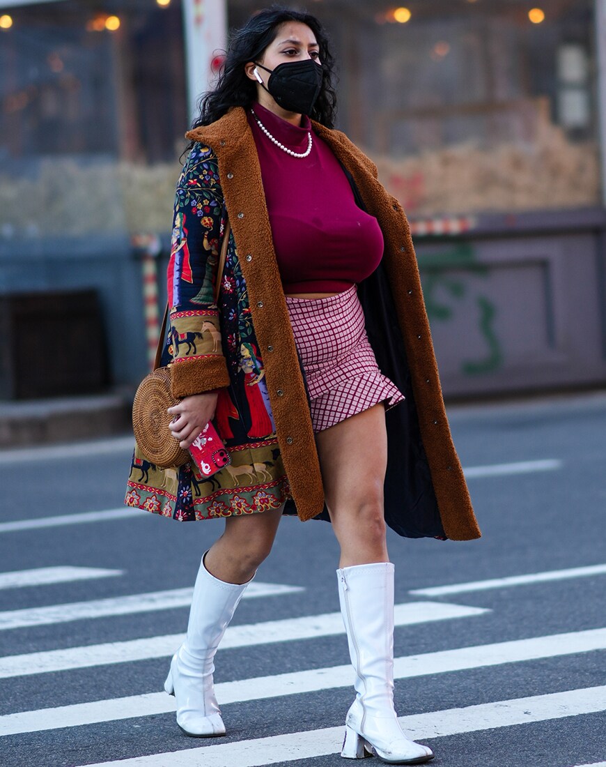 Person wears white knee-high boots and a patterned mini skirt with a dark pink rollneck and a big coat. | ASOS Style Feed