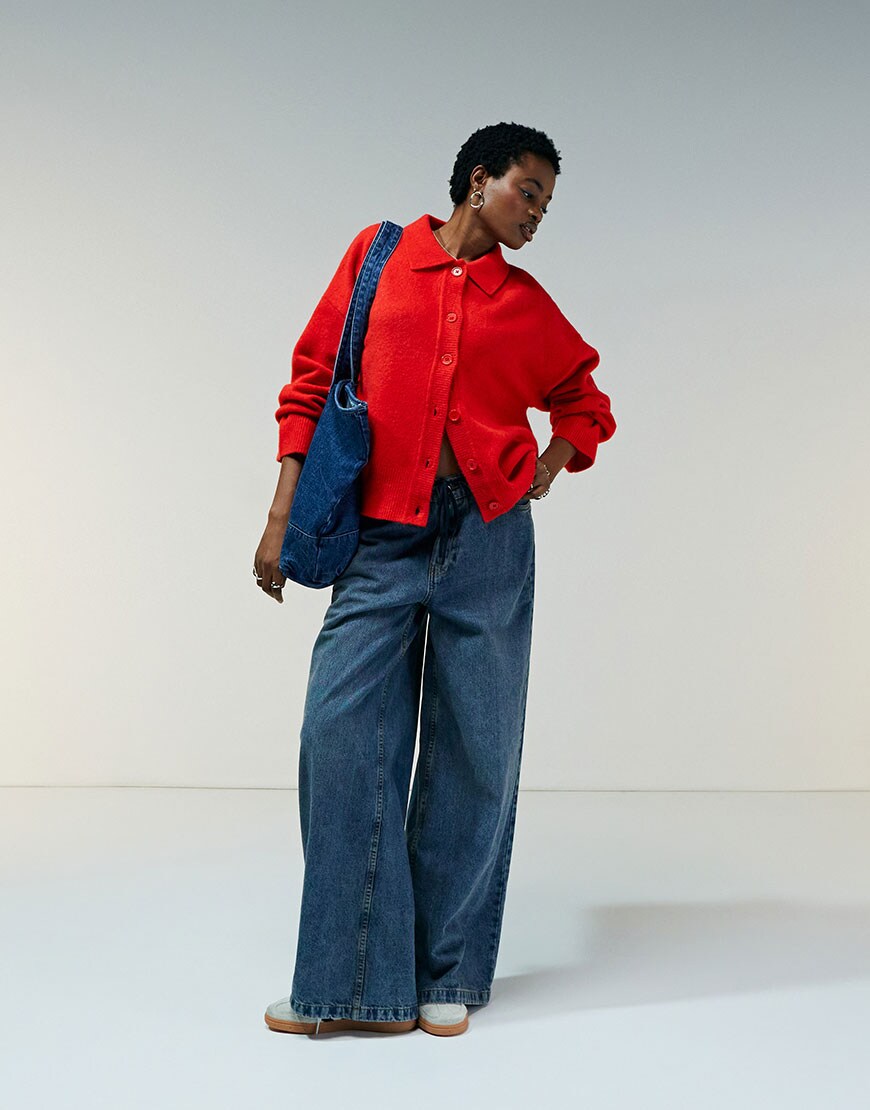 model wearing red cardigan and blue jeans