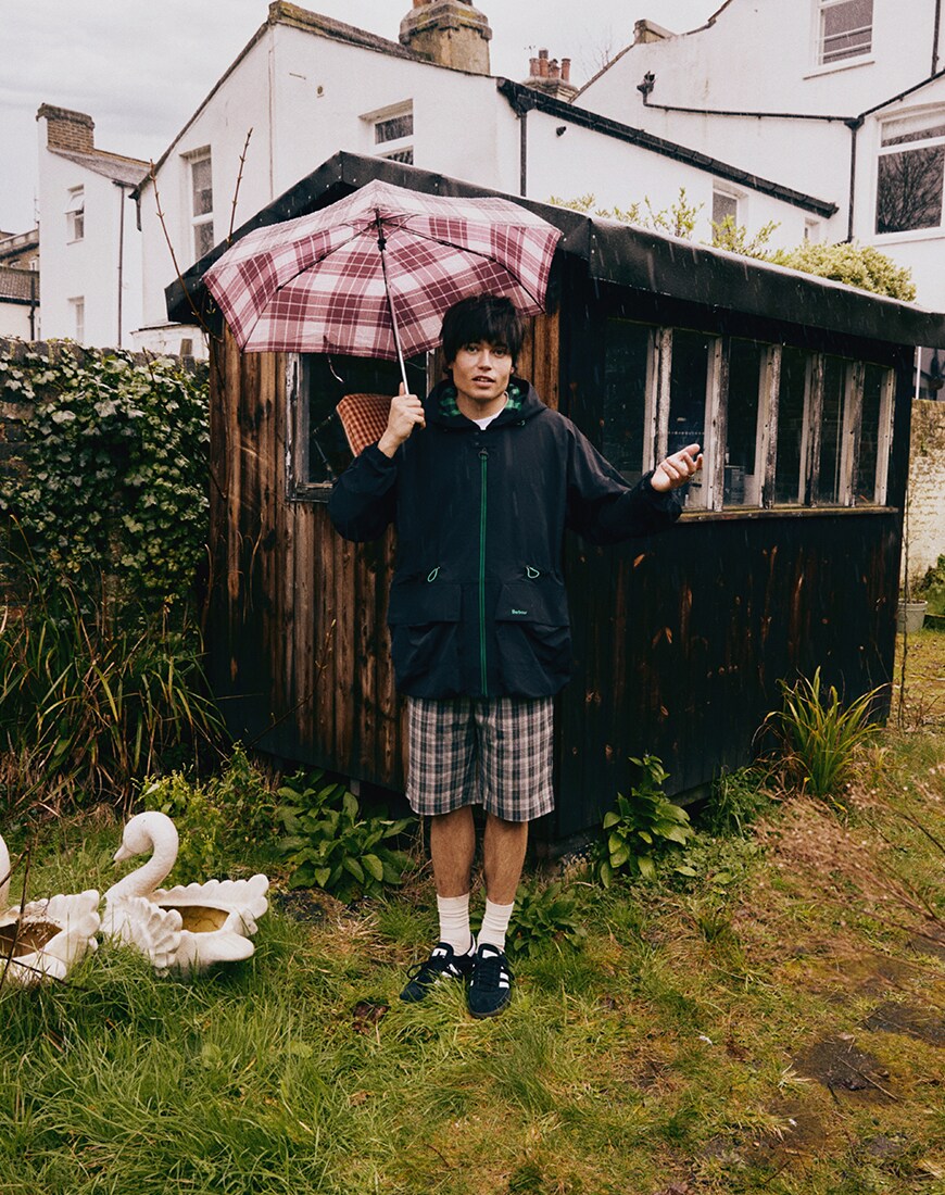 Snake Denton in a Barbour jacket holding an umbrella