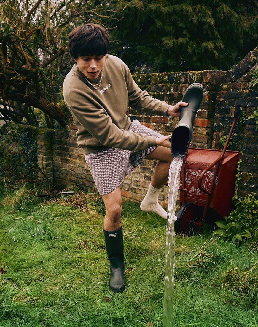 Snake wearing sweatshirt and shorts pouring water out of boot