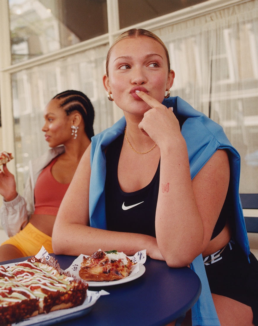 Woman wearing black Nike sports bra with pastries on the table