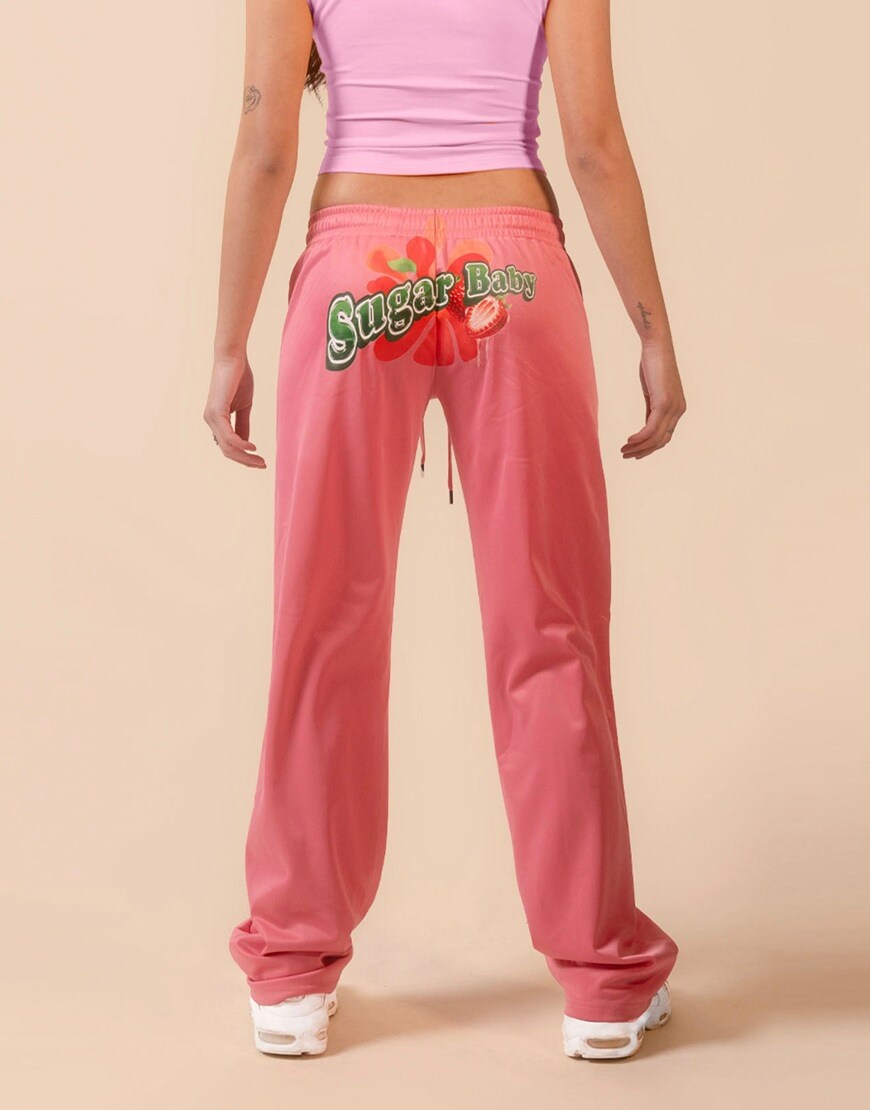 Woman wearing hot pink satin joggers with slogan