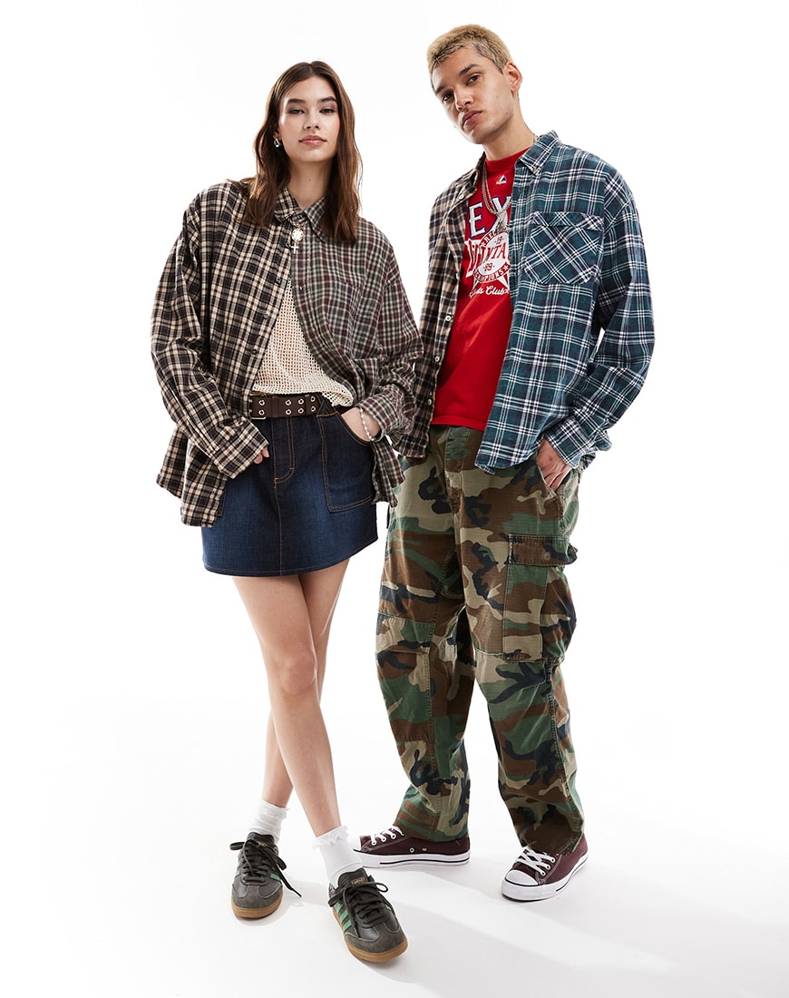 Man and woman standing wearing plaid shirts and denim
