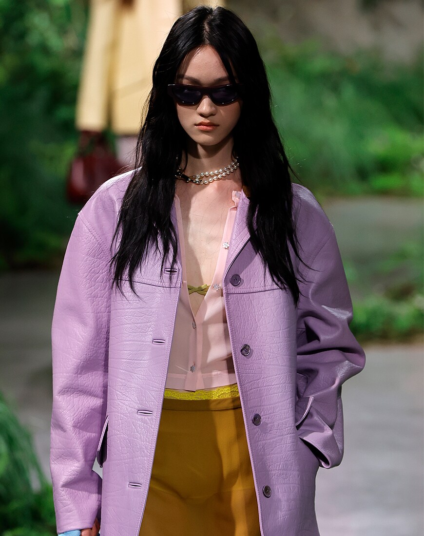 Woman wearing purple leather look oversized jacket with colourful underlayers