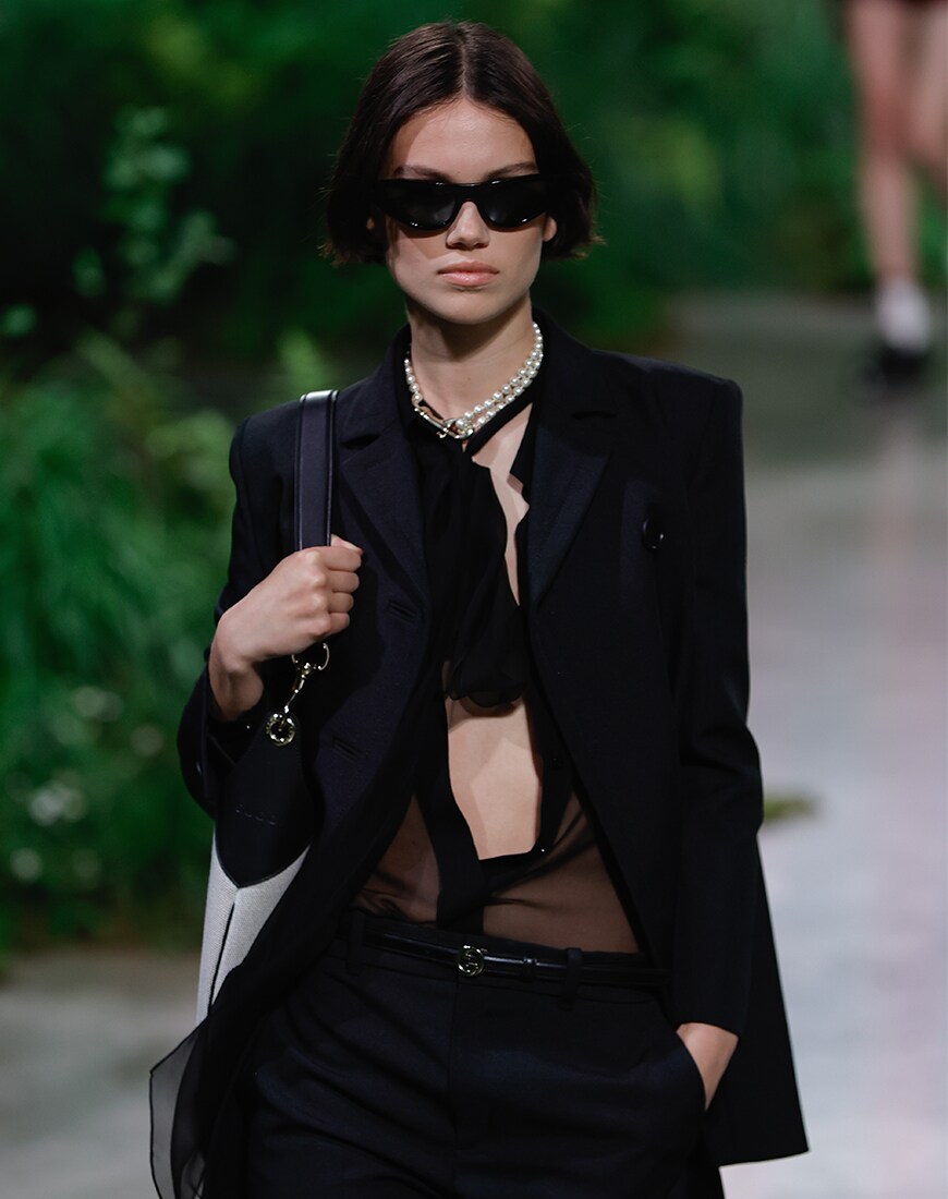 Woman wearing sheer black mesh top underneath a black blazer