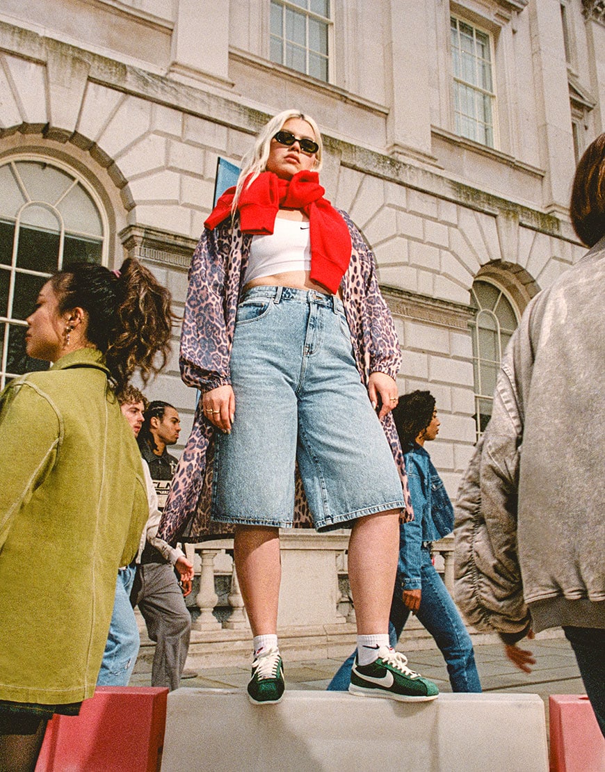 Model wearing Nike sports bra, jorts and a leopard print raincoat | ASOS Style Feed