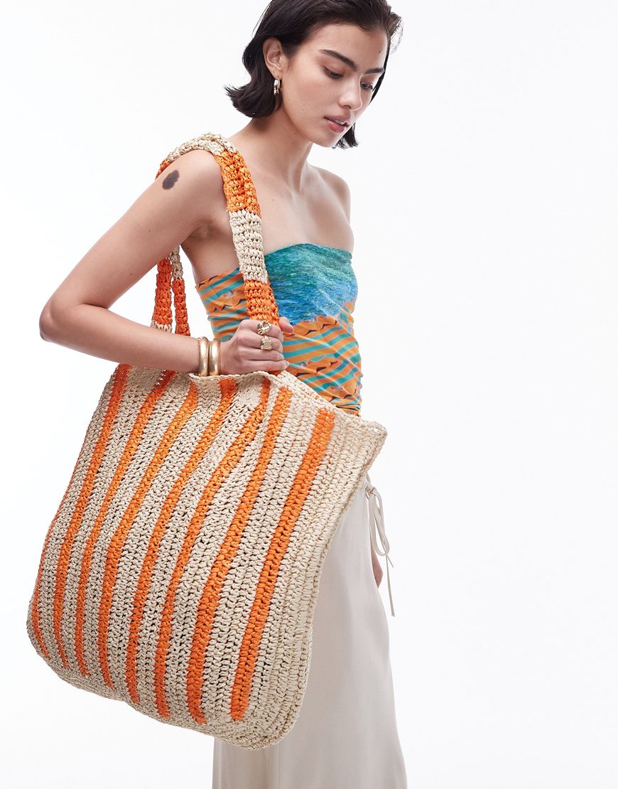 Model wearing a bikini holding large woven crochet tote bag