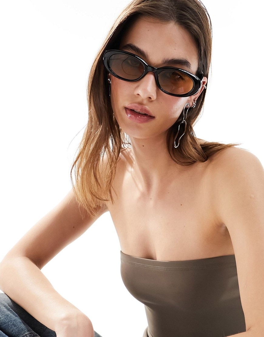 Model wearing black-rim oval shaped sunglasses with orange lenses