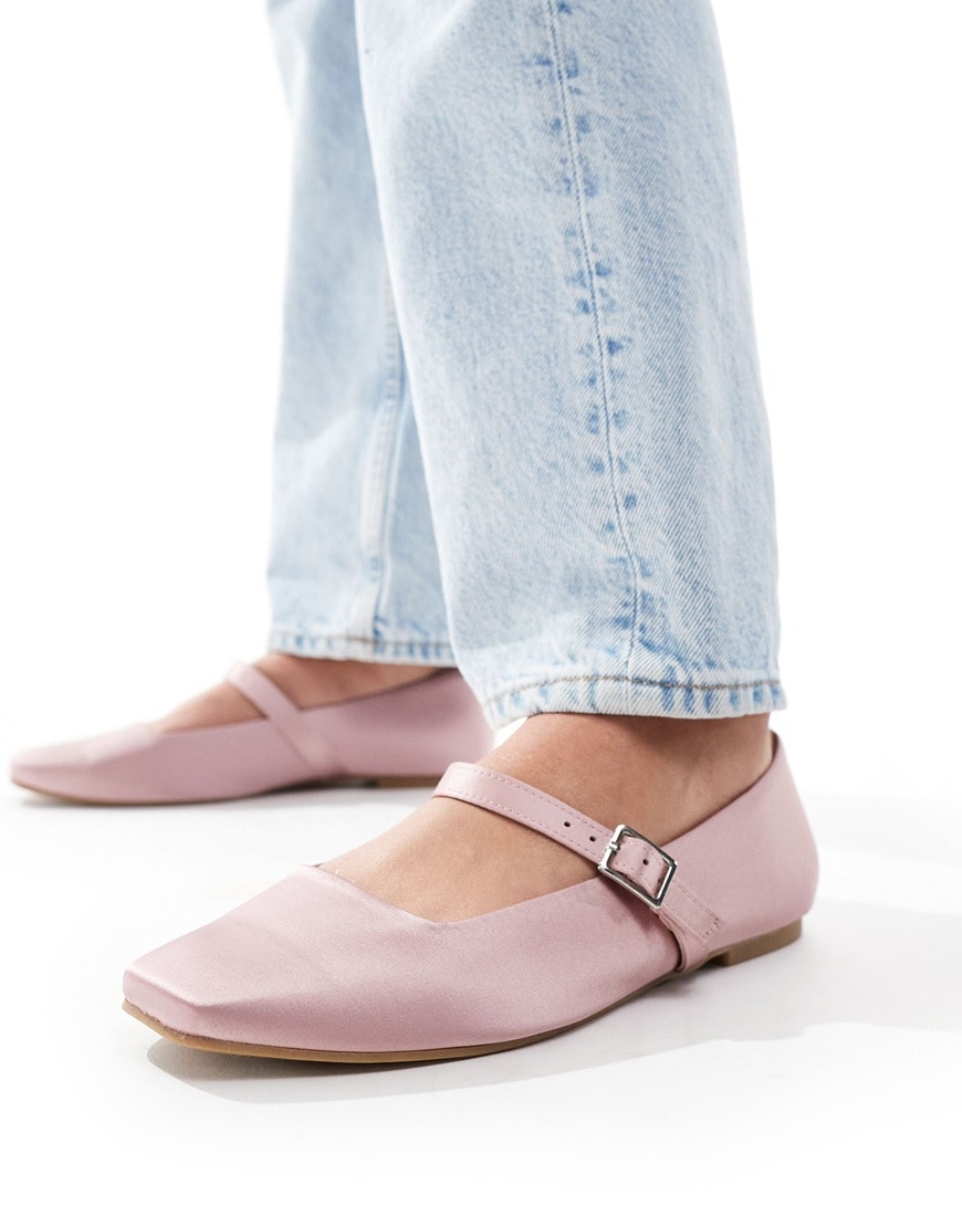 Woman wearing pink satin ballet flats and jeans