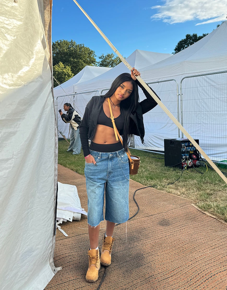 Kenza in crop top next to tent. | ASOS Style Feed