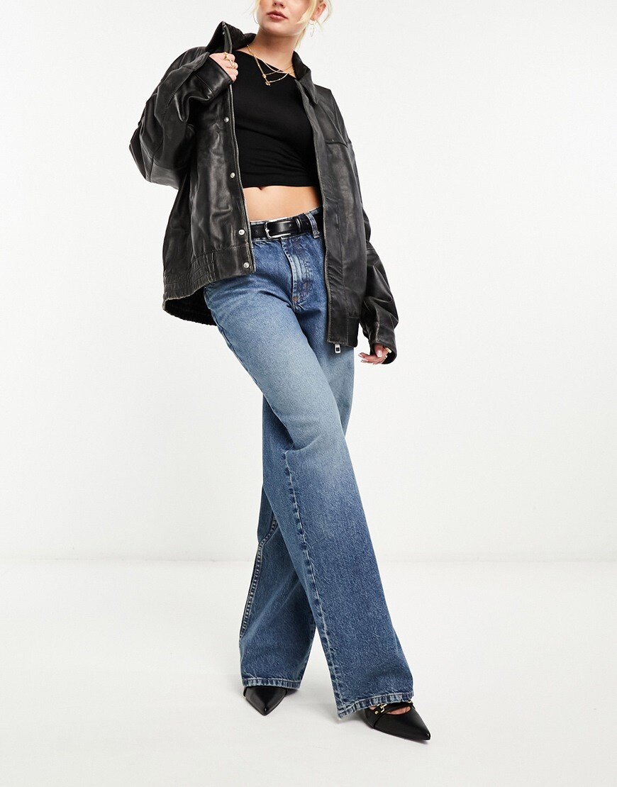 Woman wearing blue baggy boyfriend jeans and black biker jacket