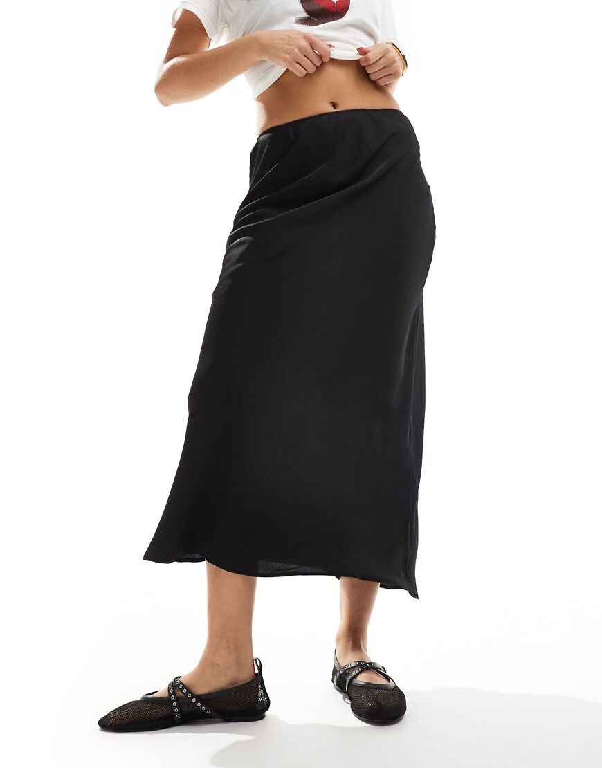 Woman wearing white shirt and black midi satin skirt