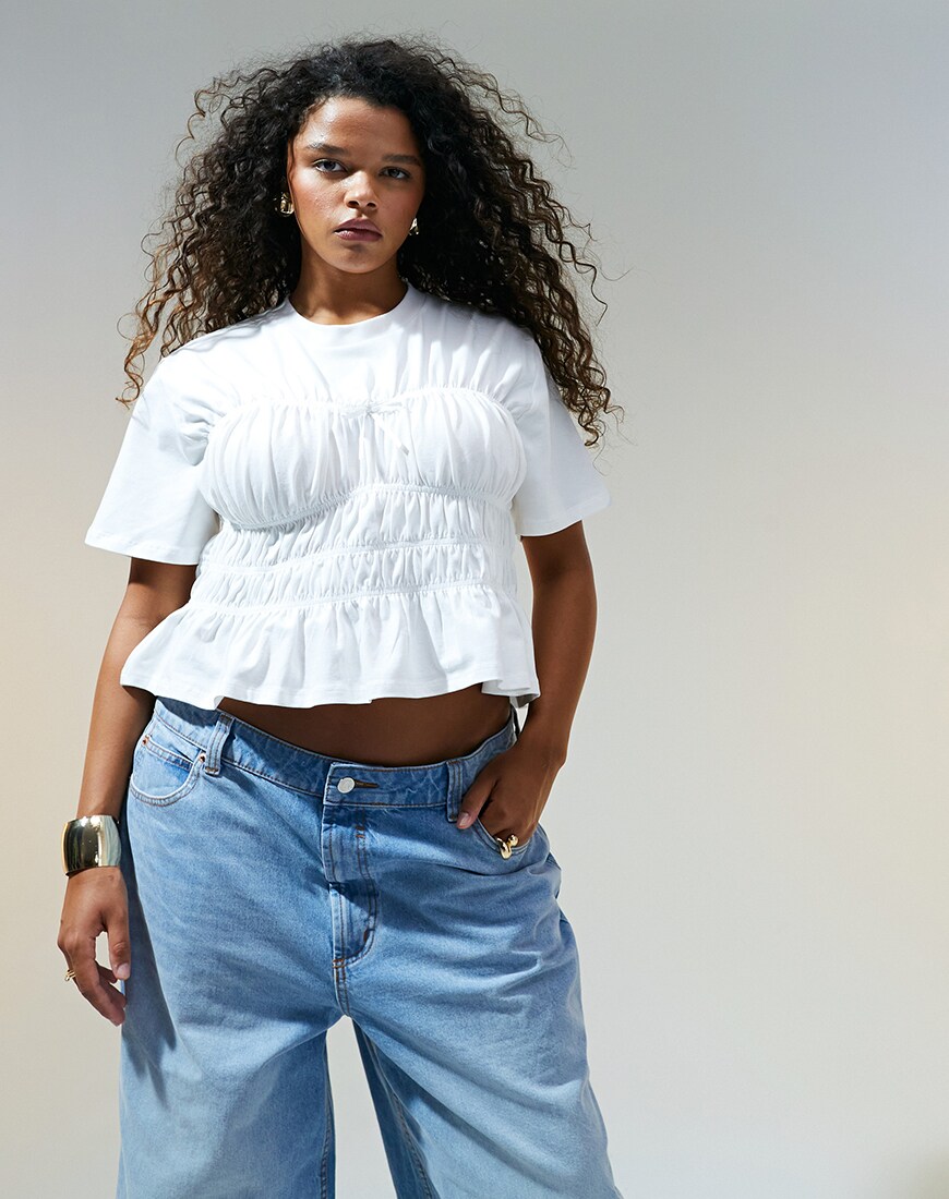 Woman wearing white ruched waist top with light blue jeans