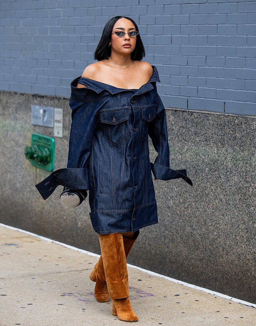 A guest wears dark denim jeans dress, brown wild leather boots outside Area during New York Fashion Week . | ASOS Style Feed