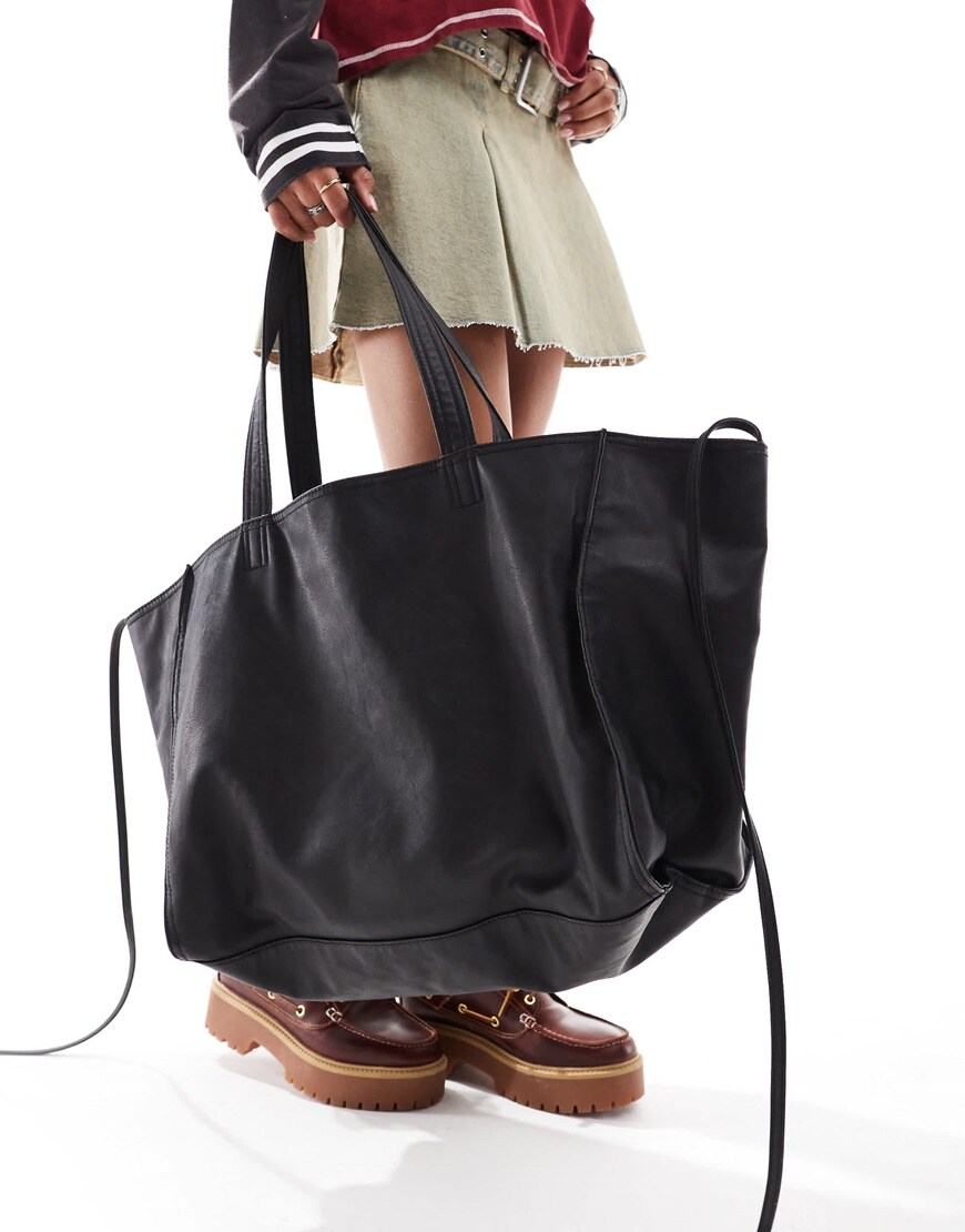 Model holding black supersized leather-look tote bag