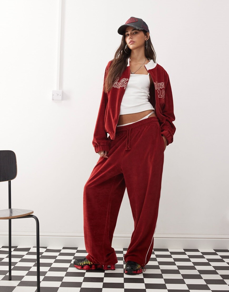 Model wearing red velour tracksuit duo