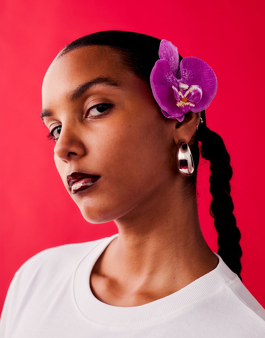 Woman wearing white t-shirt with a purple flower in hair | ASOS Style Feed