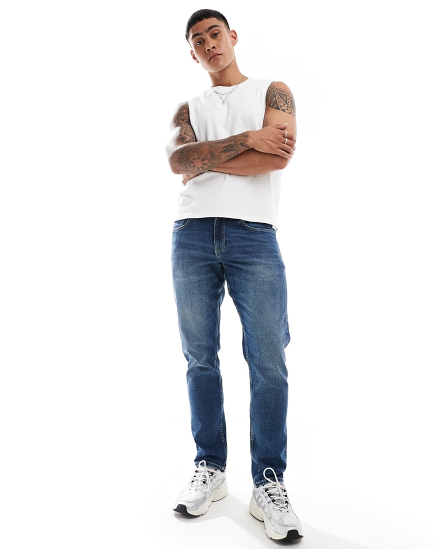 A man wearing slim fit jeans with a white tank top | ASOS Style Feed