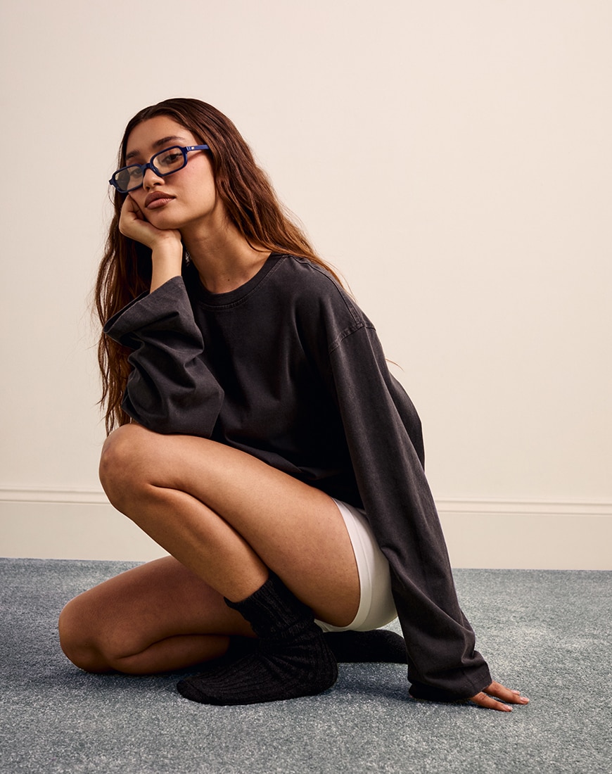 Woman crouched down earring white shorts and grey sweatshirt