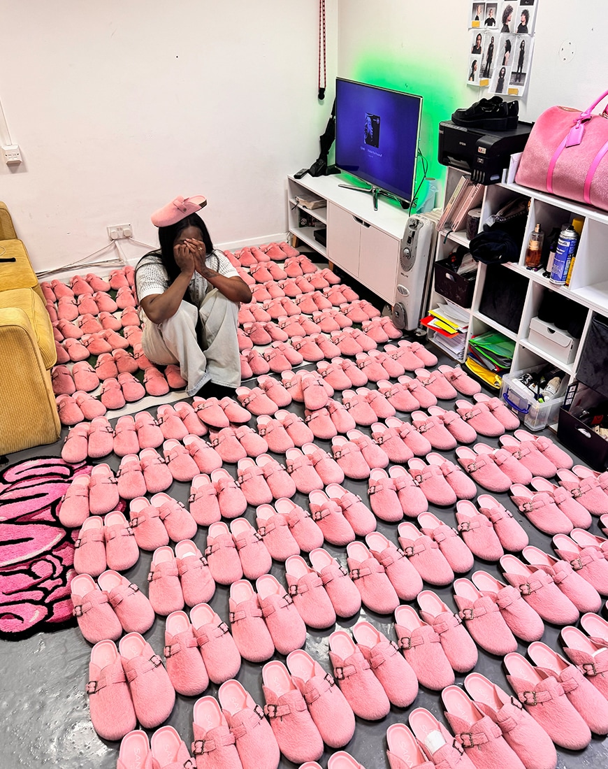 Liz Sanya seated among a floor full of pink SANYA clogs
