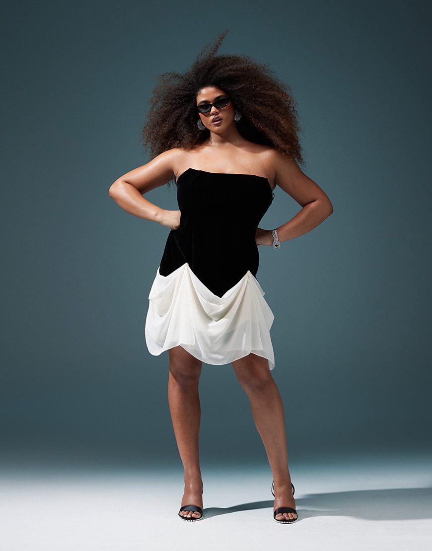 Model wearing black corset dress with white draped skirt portion