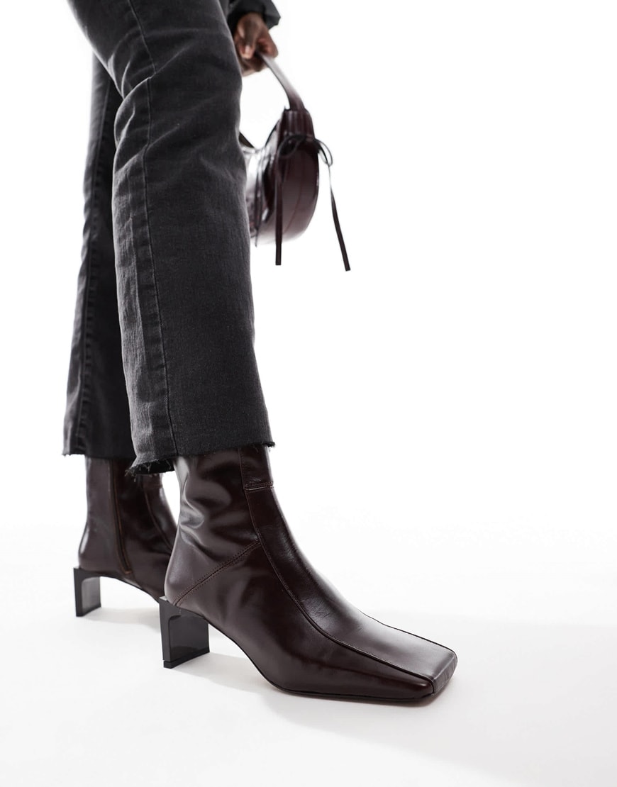 Model wearing black square-toe boots with black jeans