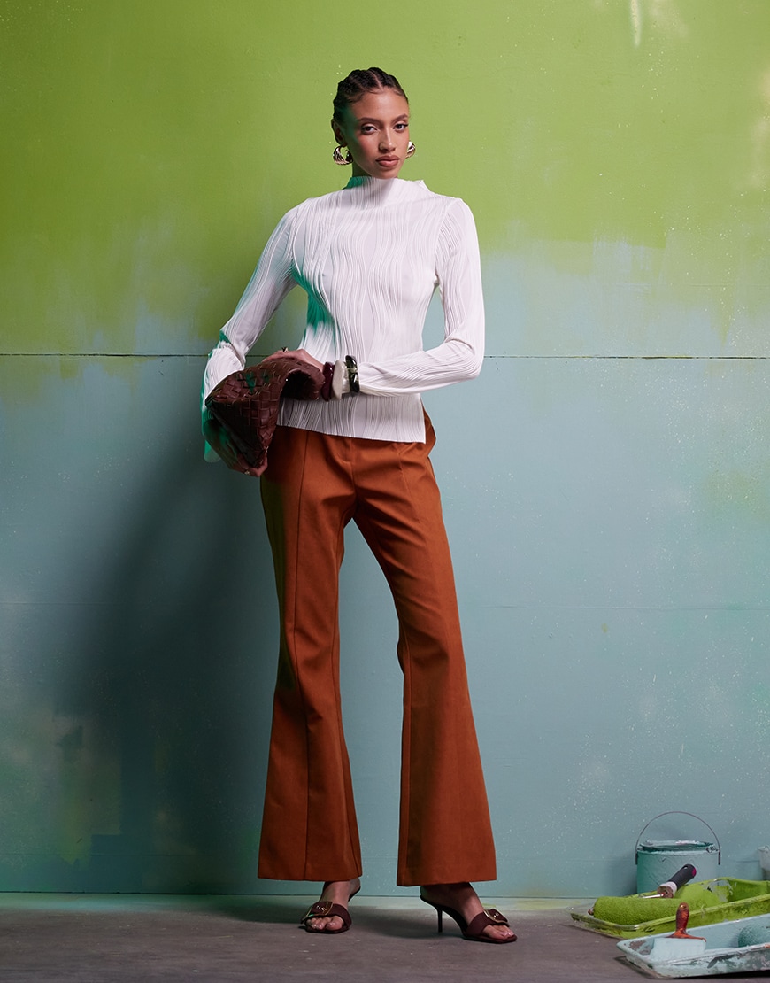 Model wearing white long-sleeve plies top with suede trousers