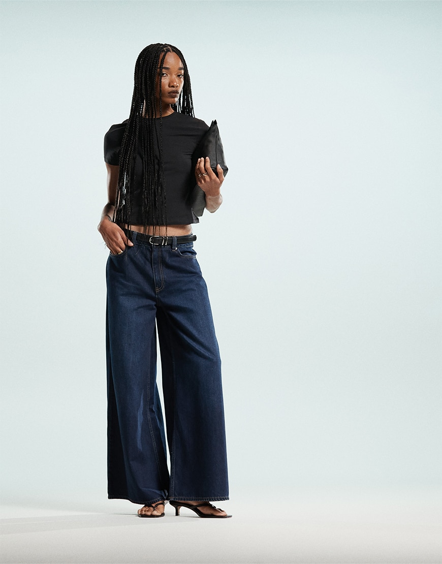 Model wearing black top and dark blue jeans