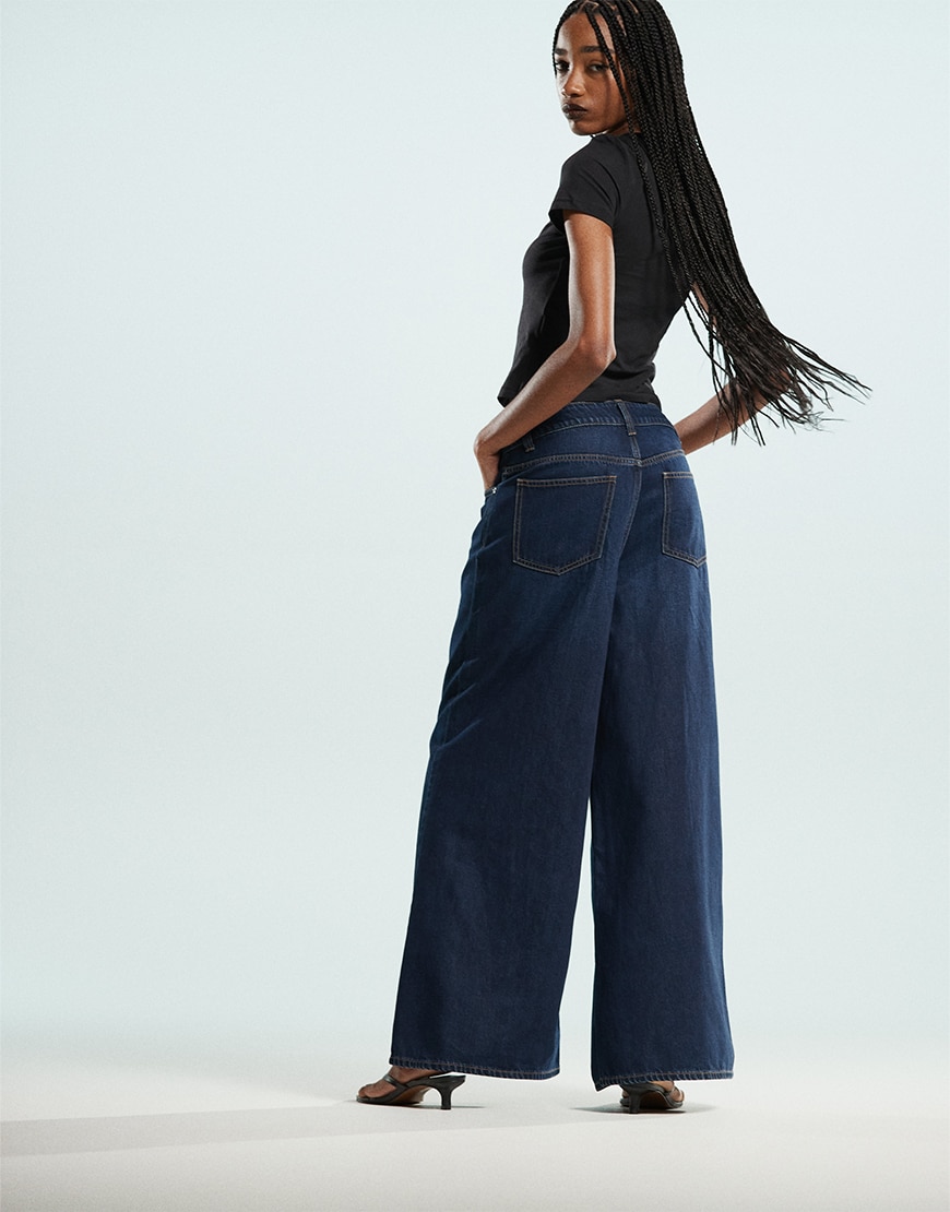 Model wearing black top and dark blue jeans