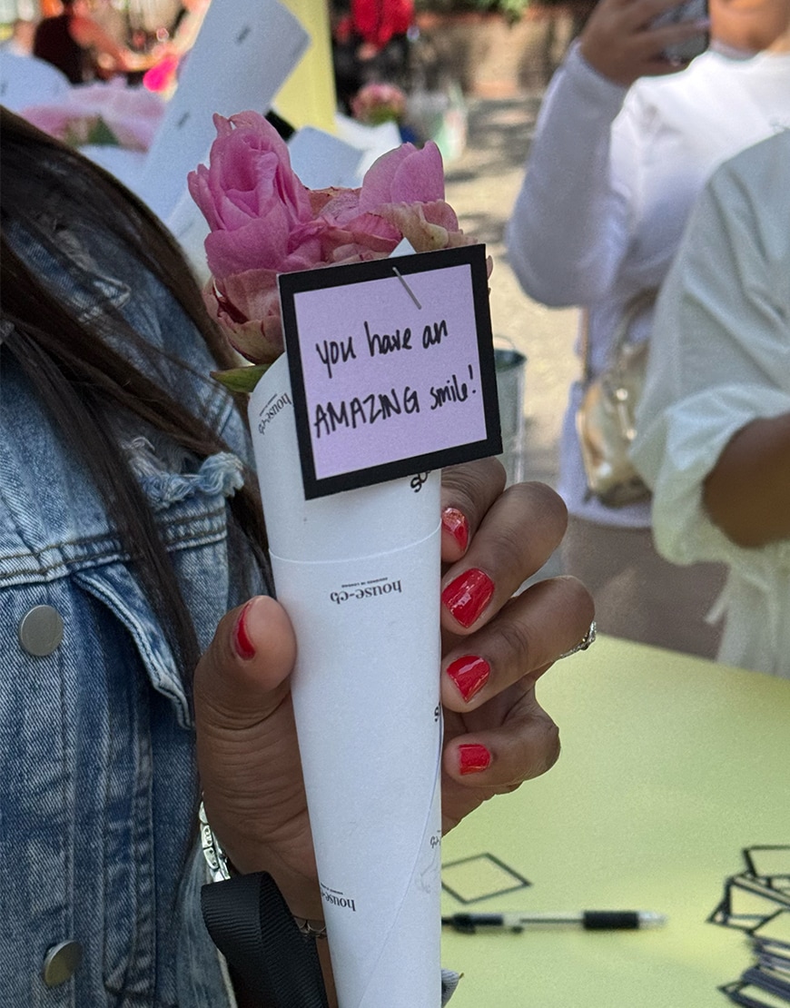 Woman with red nails holding a peony with message "you have an amazing smile".