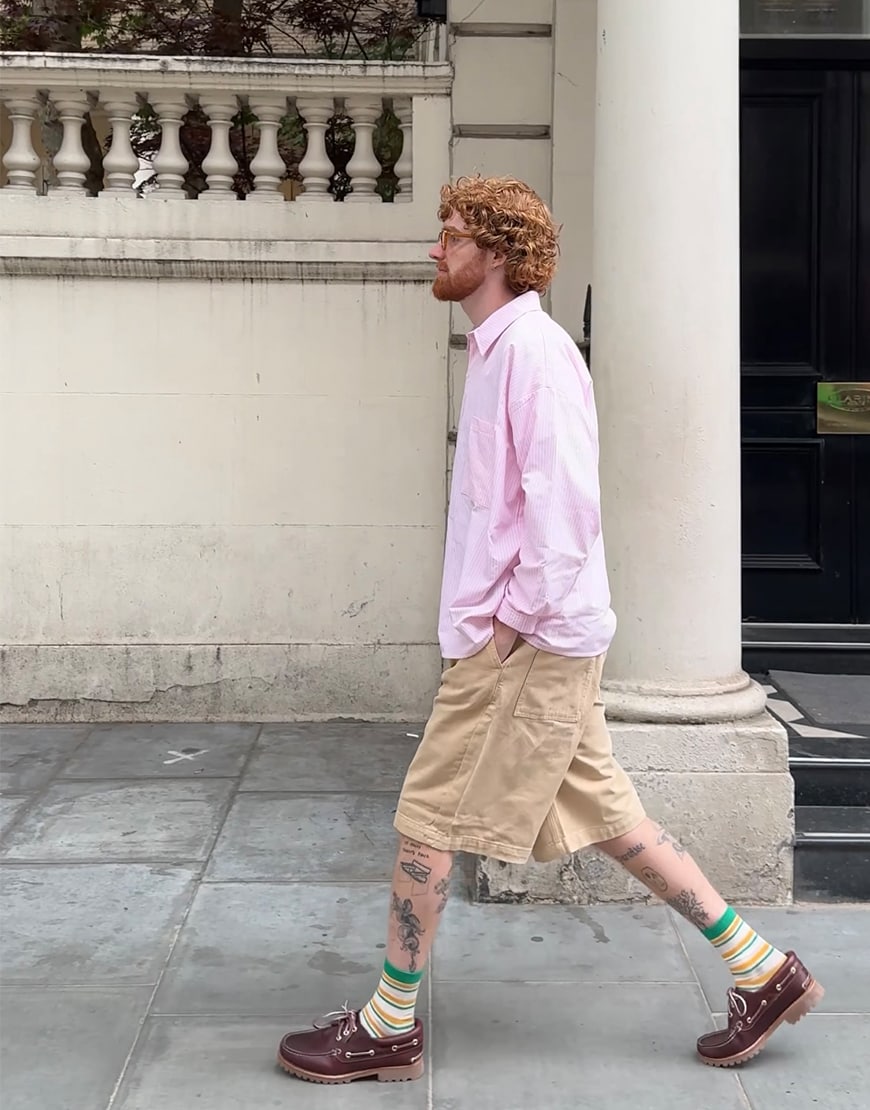 Man wearing a pink shirt, chino shorts and Timberland boat shoes