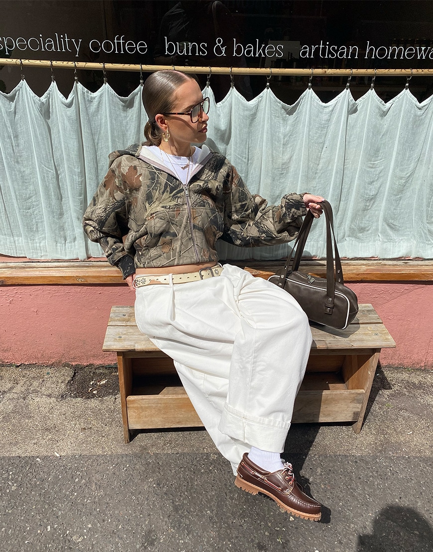 Natalie wearing white trousers and a green hoodie