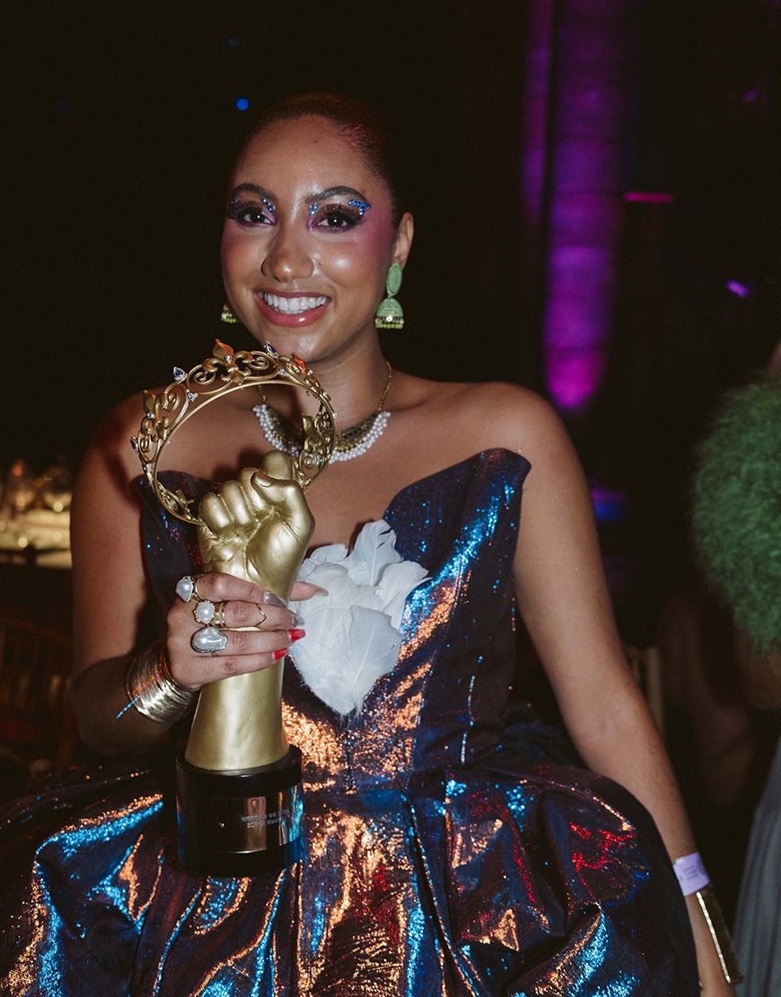 Woman holding a gold award while seated