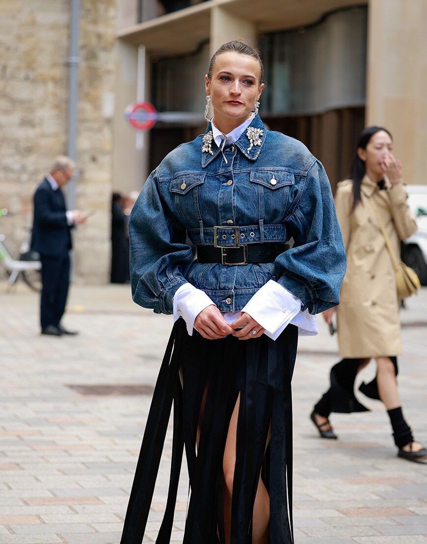 A woman wearing a cinched denim jacket and black skirt at London Fashion Week | ASOS Style Feed