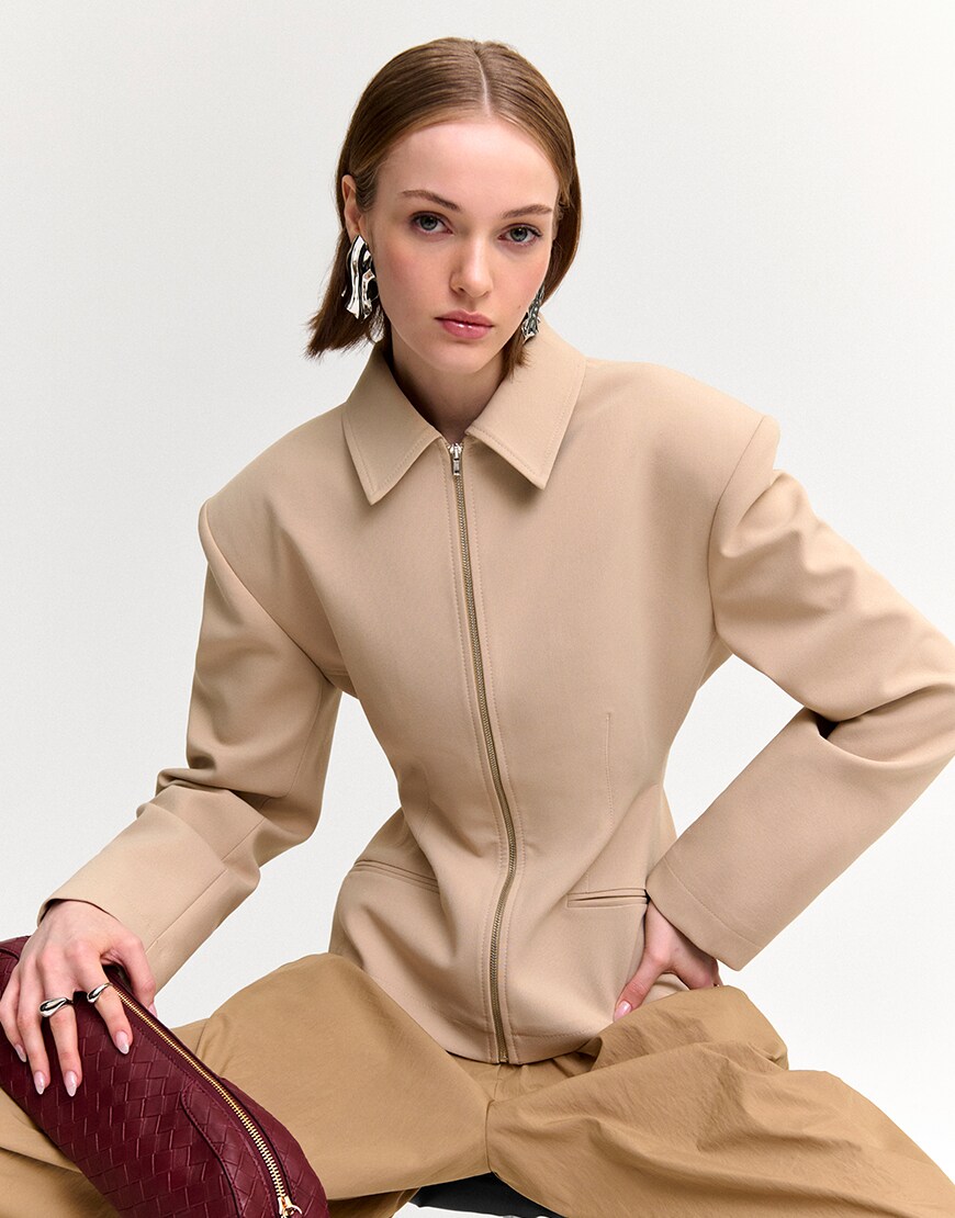 Woman wearing a neutral cinched-waist jacket