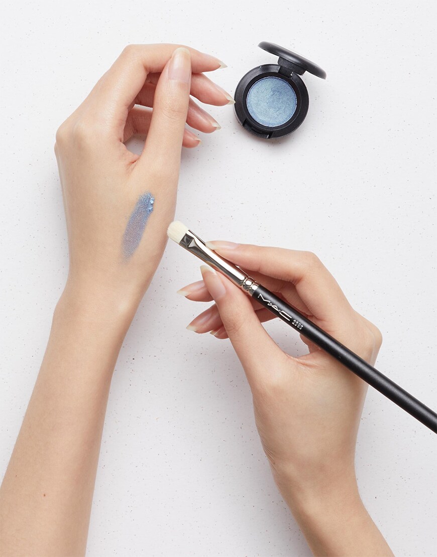 Woman applying blue eyeshadow to her hand