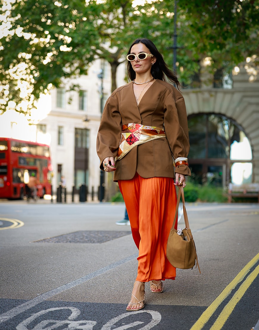 Woman wearing bright orange skirt and silk scarf at London Fashion Week | ASOS Style Feed